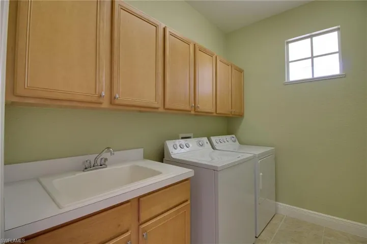 Laundry room with washing machine and dryer, cabinet space, and light tile patterned floors
