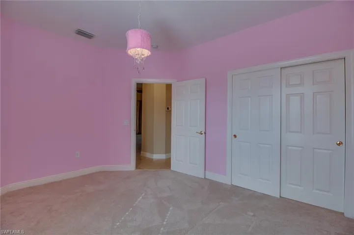 Unfurnished bedroom with light carpet, a chandelier, and a closet