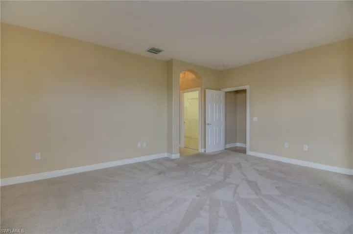 Empty room with arched walkways and light colored carpet