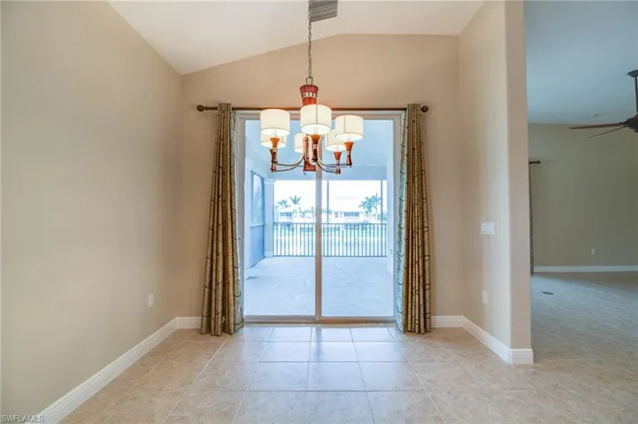 Unfurnished room featuring lofted ceiling, a chandelier, light tile patterned floors, and ceiling fan
