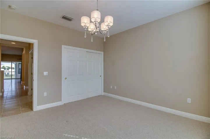 Unfurnished bedroom with light carpet, a chandelier, a closet, and light tile patterned floors