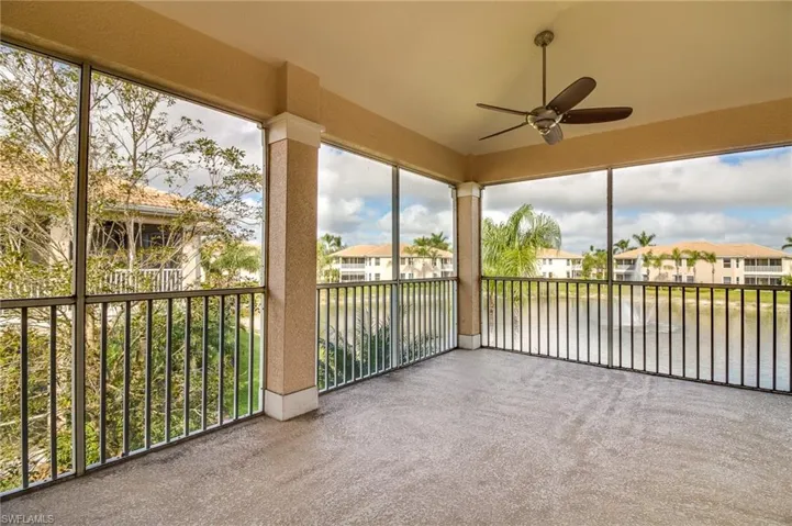 Unfurnished sunroom with a water view, carpet floors, a residential view, and a textured wall