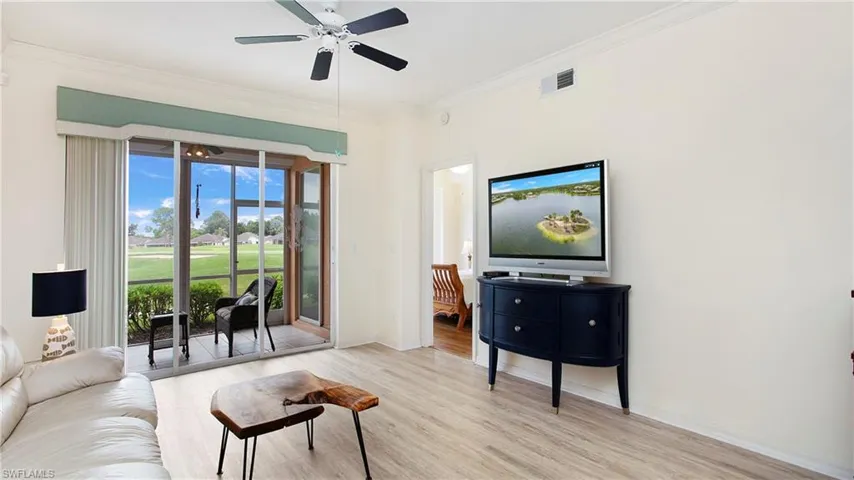 Living room with crown molding, ceiling fan, and light hardwood / wood-style floors