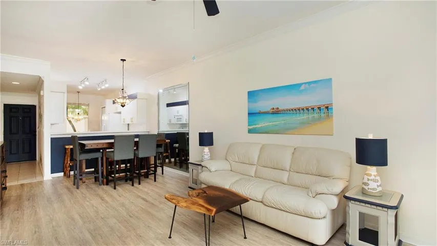 Tiled living room featuring ceiling fan with notable chandelier and ornamental molding