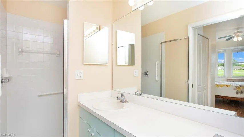 Bathroom with a shower with door, vanity, and ceiling fan