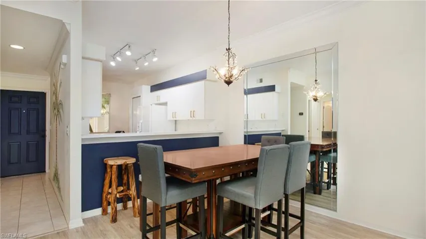 Tiled dining area with a notable chandelier, rail lighting, and ornamental molding