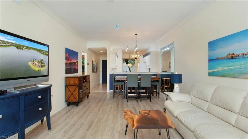 Living room featuring light hardwood / wood-style flooring, a chandelier, and ornamental molding