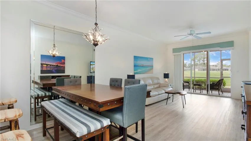 Dining space featuring ceiling fan with notable chandelier, crown molding, and light wood-type flooring