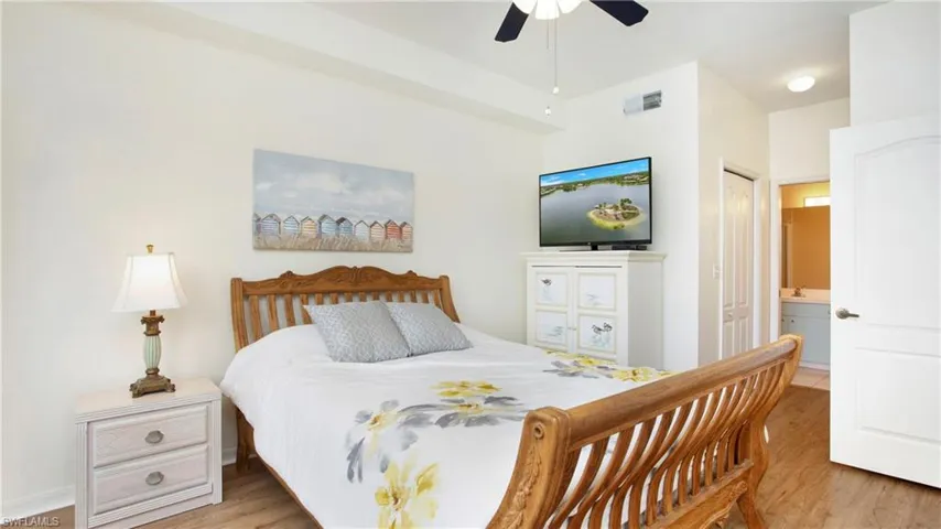 Bedroom featuring a closet, light hardwood / wood-style flooring, ensuite bathroom, and ceiling fan