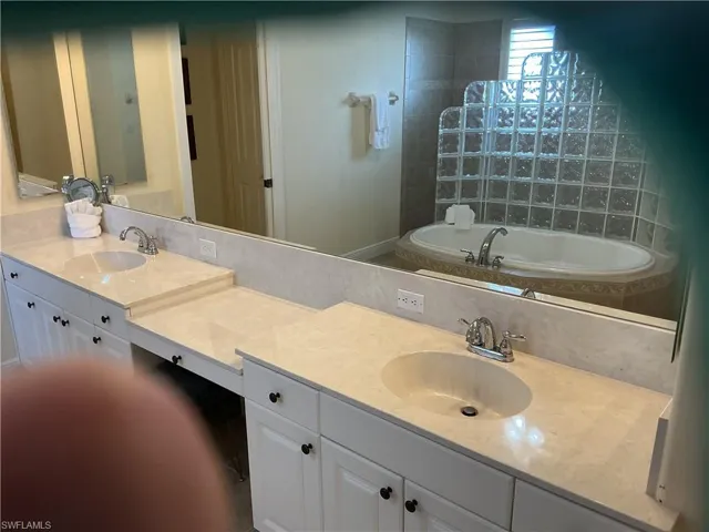 Bathroom featuring double vanity, a bath, and walk in shower