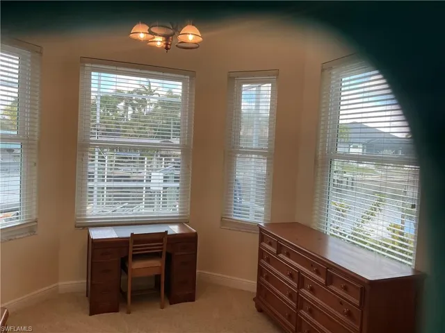 Unfurnished office with healthy amount of natural light, light colored carpet, and hanging lights