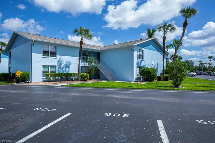 View of building exterior featuring stairway and uncovered parking