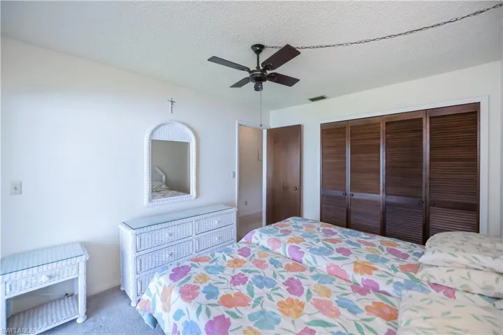Bedroom featuring a textured ceiling, carpet floors, ceiling fan, and a closet