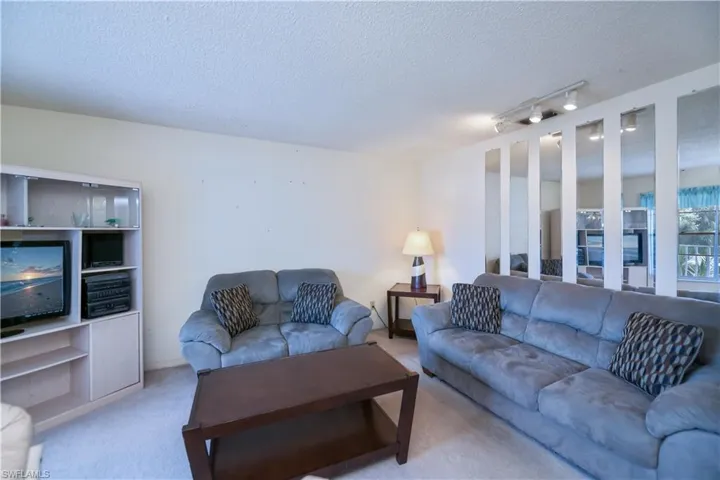 Carpeted living room featuring a textured ceiling and rail lighting