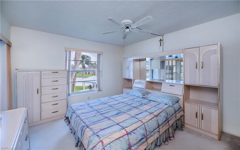 Bedroom featuring a textured ceiling, light colored carpet, and a ceiling fan