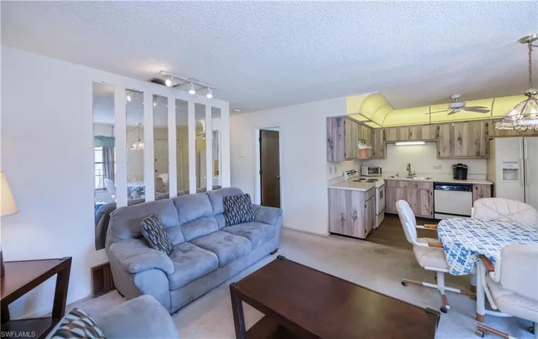 Living area featuring a chandelier, light carpet, a textured ceiling, and a ceiling fan