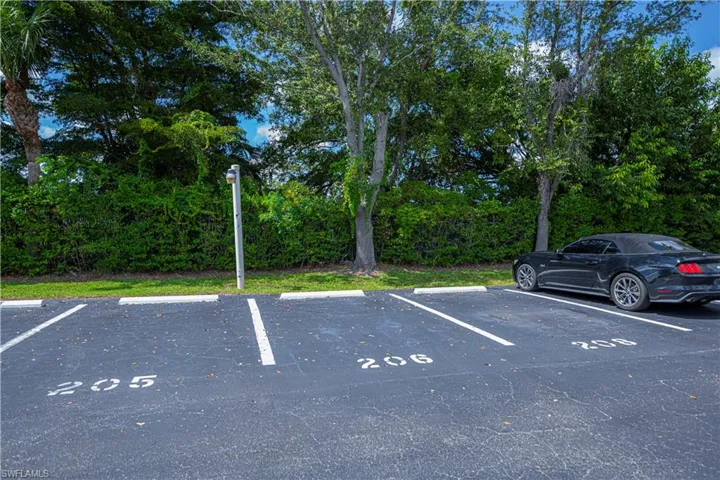 Uncovered parking lot with view of wooded area