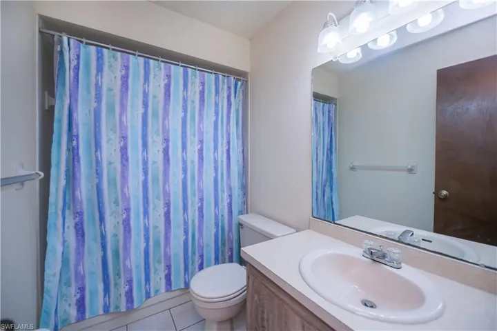 Full bathroom with tile patterned flooring, vanity, and a shower with curtain