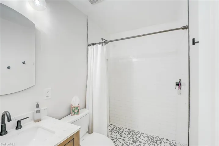 Bathroom featuring toilet, vanity, and a shower with curtain