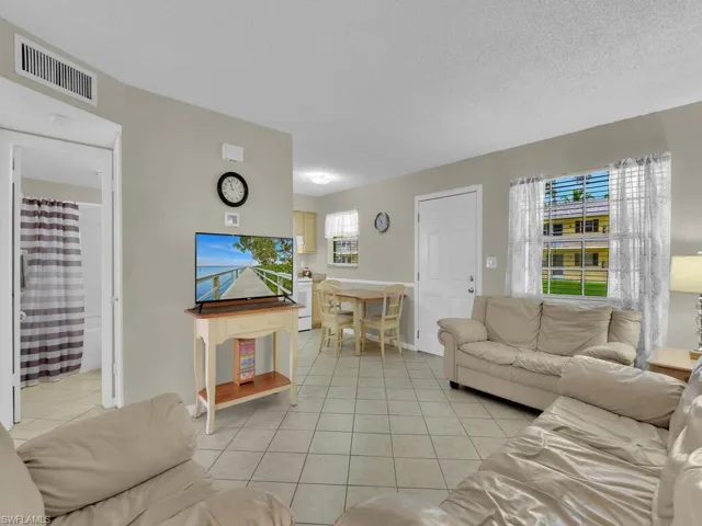 Tiled living room with a textured ceiling, washer / dryer, and a healthy amount of sunlight