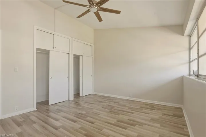 Unfurnished bedroom featuring multiple closets, light wood-style floors, and ceiling fan