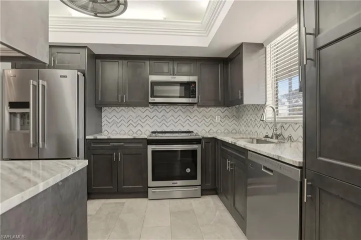 Kitchen featuring stainless steel appliances, light stone counters, and backsplash