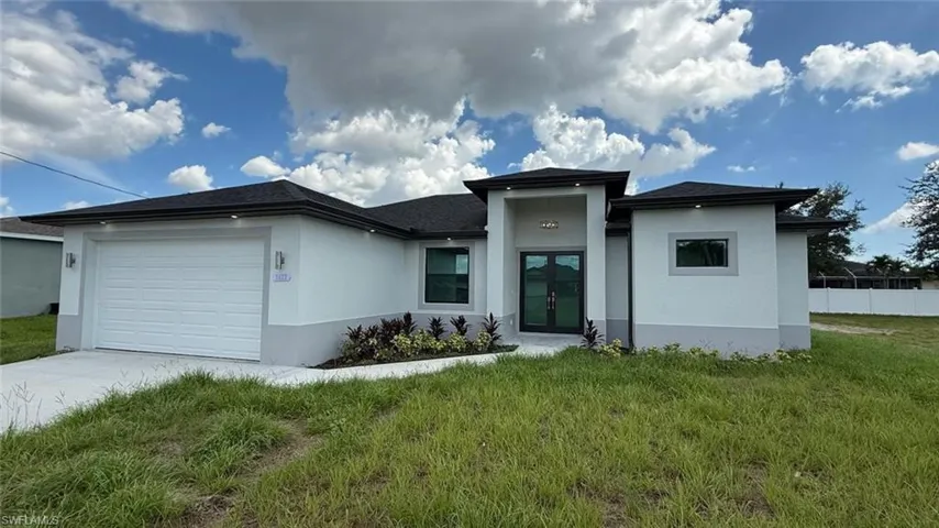 Prairie-style house with a garage, stucco siding, driveway, and french doors