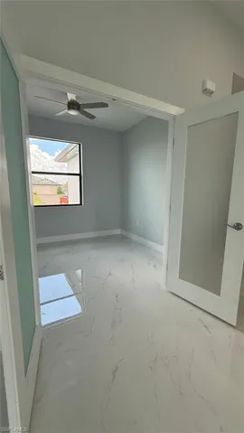 Spare room with light marble finish floors and a ceiling fan