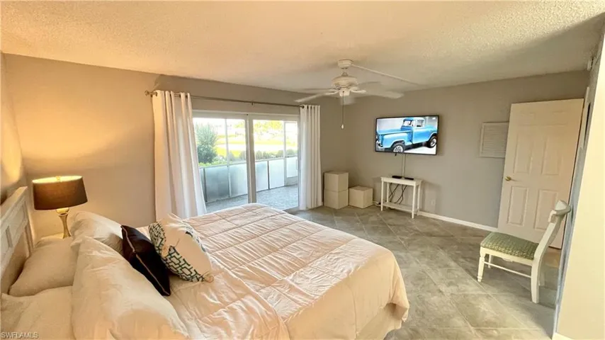 Bedroom with access to exterior, a textured ceiling, ceiling fan, and light tile patterned flooring