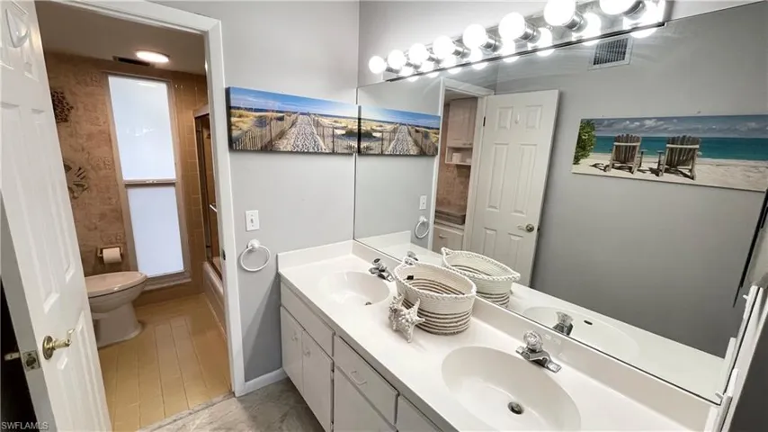 Full bath with double vanity and enclosed tub / shower combo