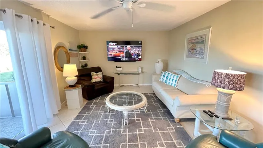 Tiled living room featuring baseboards and a ceiling fan