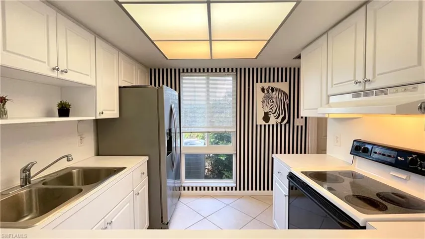 Kitchen featuring range with electric stovetop, white cabinetry, under cabinet range hood, and light countertops