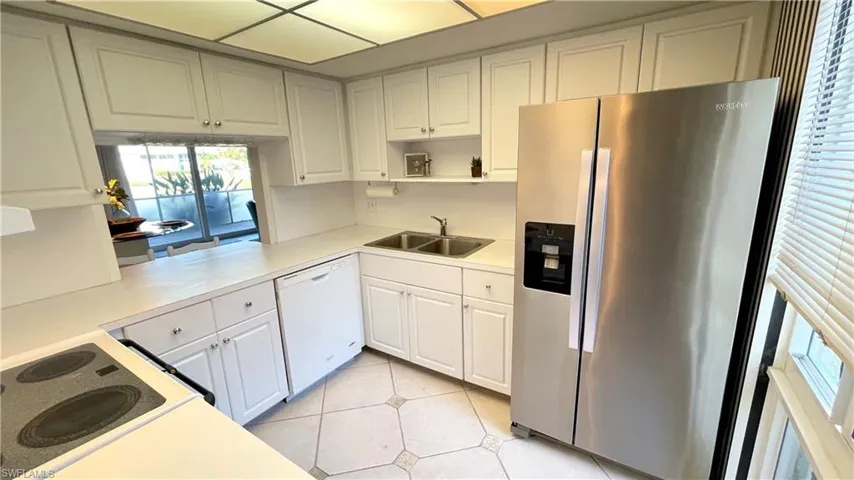Kitchen featuring stainless steel refrigerator with ice dispenser, white cabinets, light countertops, dishwasher, and light tile patterned floors