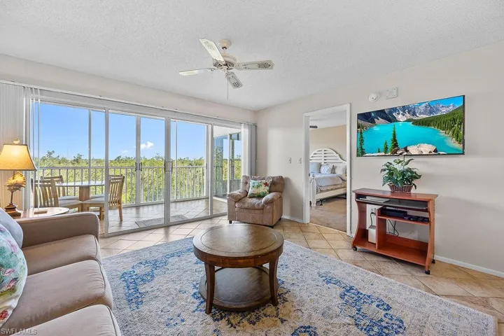 Living room with a textured ceiling, ceiling fan, and light tile patterned floors