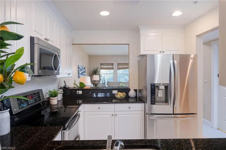 Kitchen featuring stainless steel appliances, dark stone countertops, white cabinets, and recessed lighting