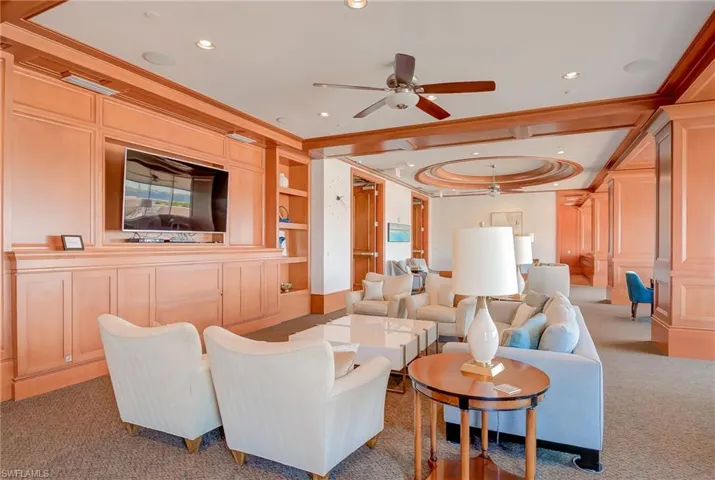 Living room with built in shelves, carpet floors, recessed lighting, ceiling fan, and ornamental molding