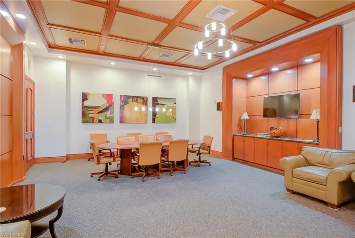 Dining area with light colored carpet, coffered ceiling, and a chandelier