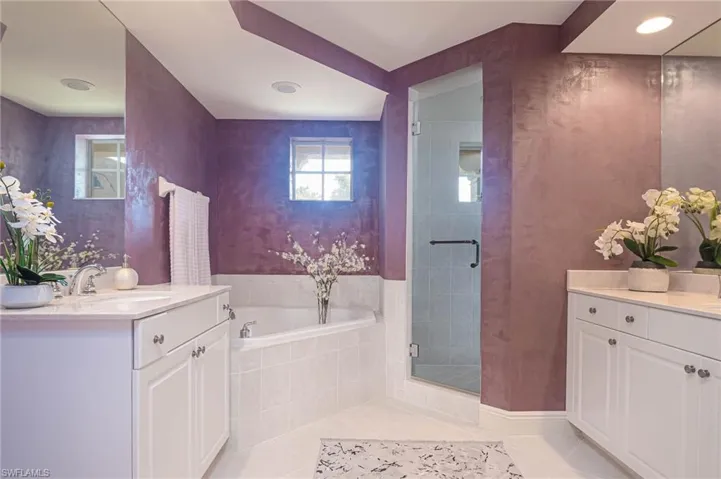 Full bathroom featuring two vanities, a bath, light tile patterned flooring, a shower stall, and recessed lighting