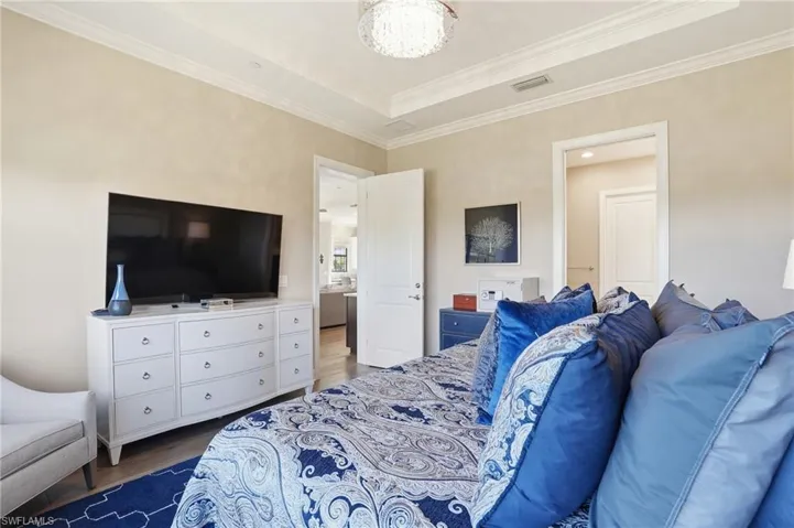 Bedroom featuring wood finished floors, crown molding, and a raised ceiling