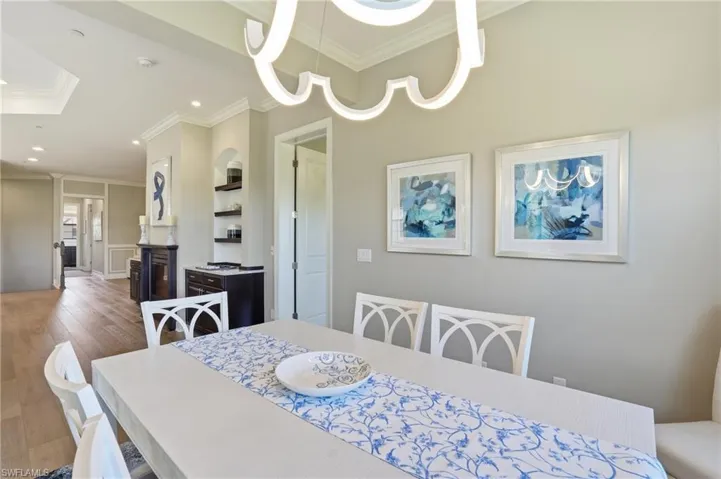 Dining area with ornamental molding, wood finished floors, and recessed lighting
