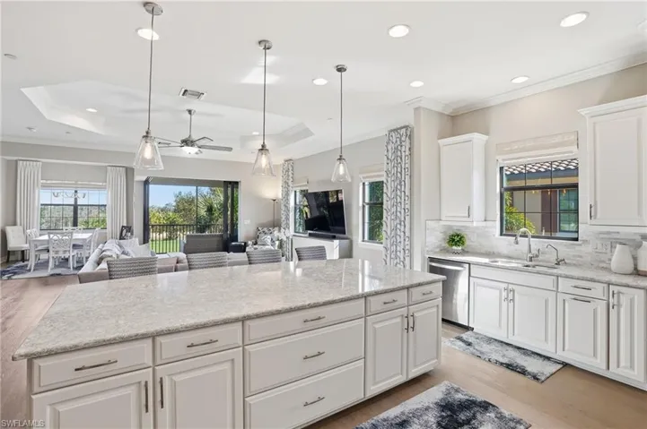 Kitchen with white cabinets, light wood-type flooring, ornamental molding, ceiling fan, and light stone countertops