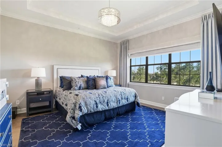 Bedroom featuring a tray ceiling, crown molding, and dark wood-style flooring
