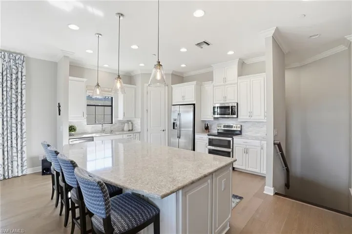 Kitchen featuring white cabinets, a breakfast bar area, crown molding, a center island, and stainless steel appliances