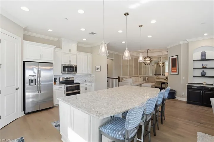 Kitchen with appliances with stainless steel finishes, decorative backsplash, ornamental molding, a large island, and a breakfast bar