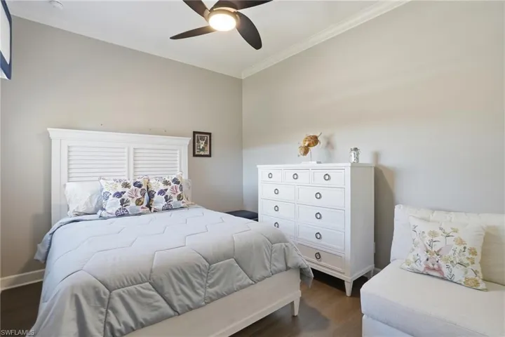 Bedroom with ornamental molding, dark wood-type flooring, and ceiling fan