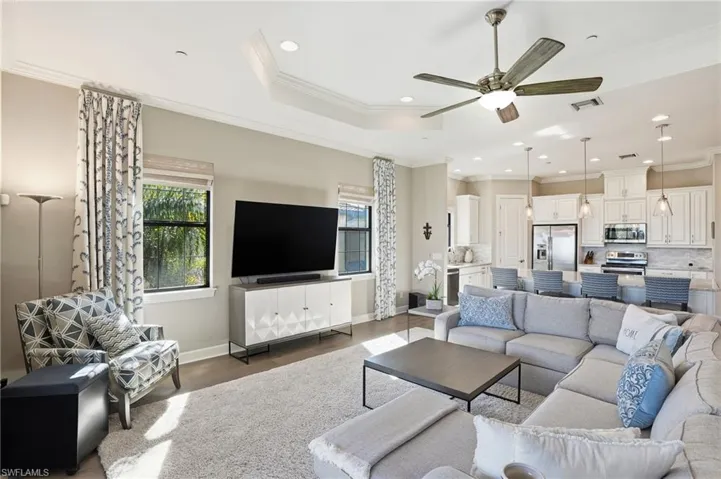 Living room featuring crown molding, plenty of natural light, ceiling fan, a raised ceiling, and recessed lighting