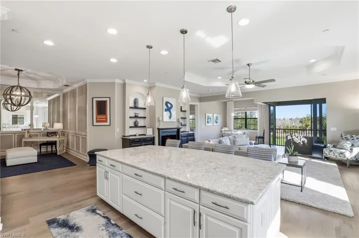 Kitchen with open floor plan, white cabinetry, crown molding, light wood-style flooring, and pendant lighting