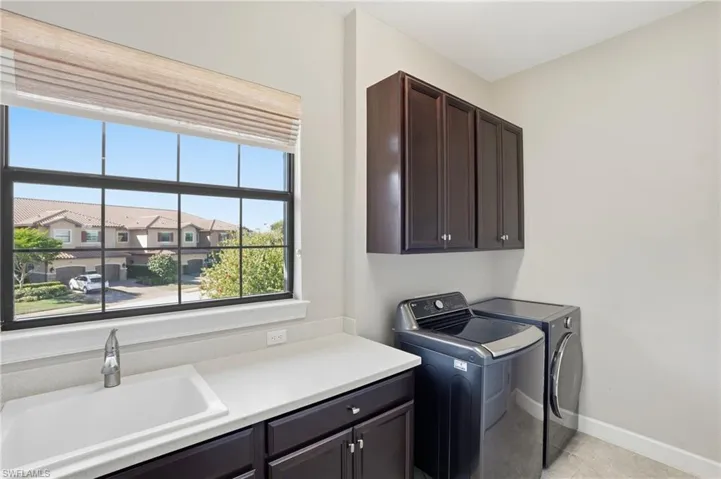 Washroom featuring washer and clothes dryer, cabinet space, and light tile patterned flooring