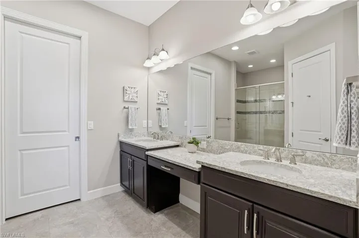 Bathroom featuring a stall shower, double vanity, and recessed lighting