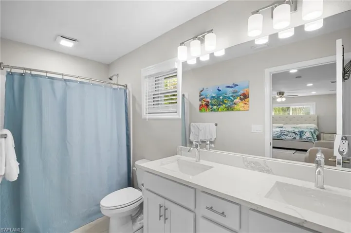 Full bath with double vanity, ensuite bathroom, plenty of natural light, and ceiling fan